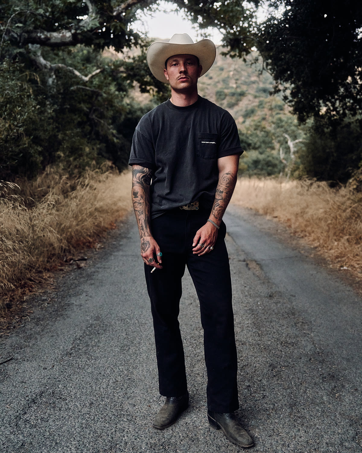 Alex McCormick on a canyon road in a straw hat and black tee